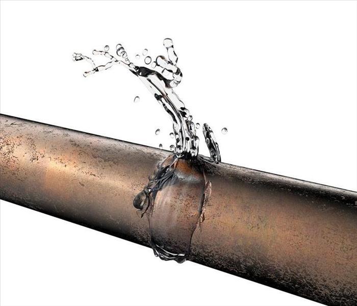 Water shoots out of a burst copper pipe