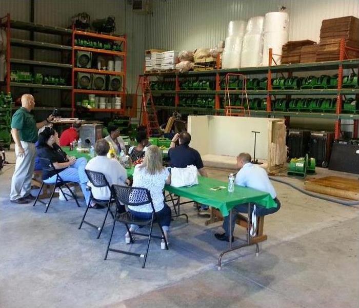 A group of employees gathers around a table in a warehouse